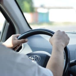 Close up of man driving with hands on the steering wheel.