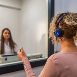 Woman sitting in a sound test booth audiologist office