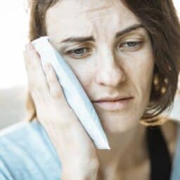 Woman holding a cold pack up to her face.