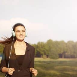 Woman listening to headphones outside.