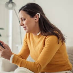 Woman wearing a hearing aid looking at her phone