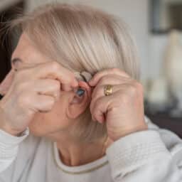Senior woman putting in her hearing aid