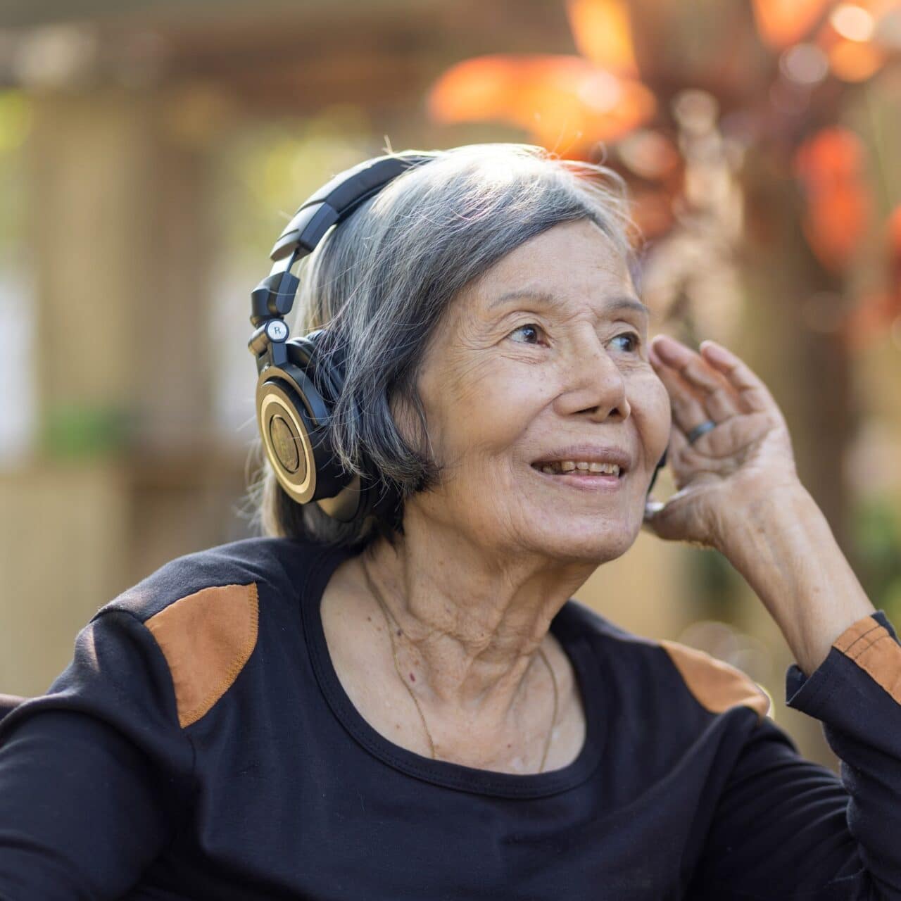 Woman with hearing aids uses over-ear headphones in the park
