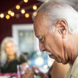 Man with a hearing aid eating with many people in a restaurant.