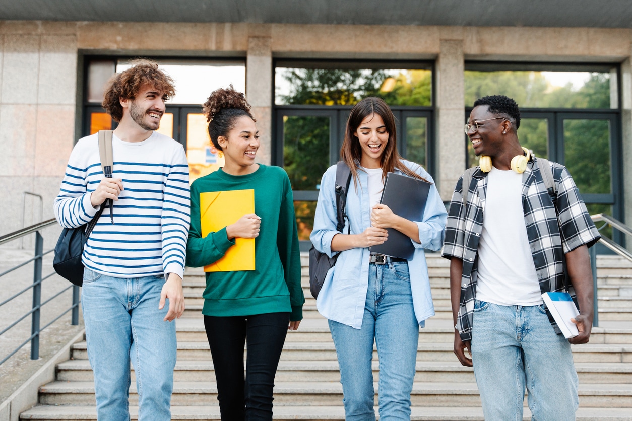 Smiling group of students walking across college campus.