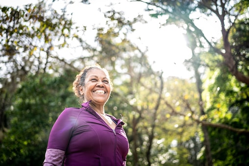 Happy, confident woman enjoying a hike in the woods.