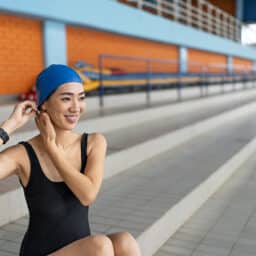 Competitive swimmer inserts swimmers' earplugs under her swim cap to prevent water from getting in her ears.