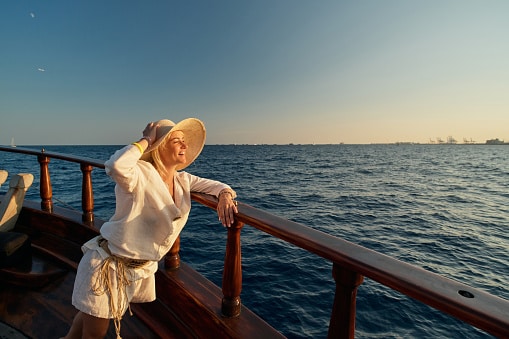 Stylish woman on a cruise standing on the boat deck looking at the waves.