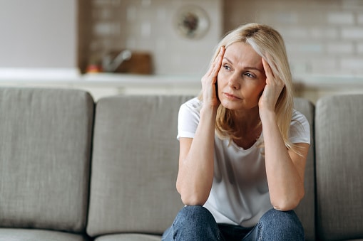 Woman with hearing loss sits at home, feeling insecure.