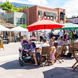 Crowd of people enjoying a local street fair and outdoor market in a quaint neighborhood on a summer day.