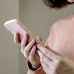 Young girl in a pink sweatshirt is looking through her smartphone. Use of modern technologies.